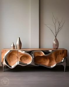 a sideboard with two vases on top of it next to a plant in a vase