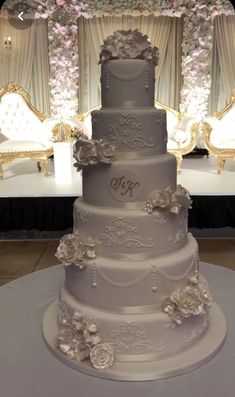 a three tiered wedding cake sitting on top of a white table covered in flowers