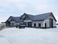 a truck is parked in front of a large gray building with two garages on each side