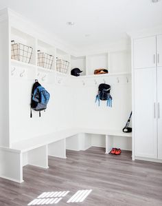 a white room with several coats hanging on the wall and shoes in the closets