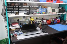 a laptop computer sitting on top of a desk next to a shelf filled with office supplies