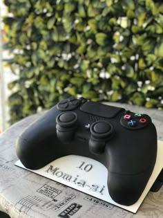 a black controller sitting on top of a table next to a green plant covered wall