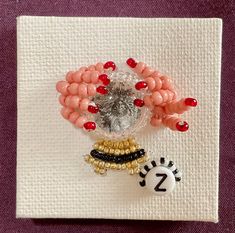 a beaded brooch with beads on it sitting on a piece of paper next to a button