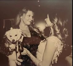 two women are talking to each other while one holds a small dog in her lap