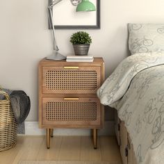 a nightstand next to a bed with a plant on it and a wicker basket