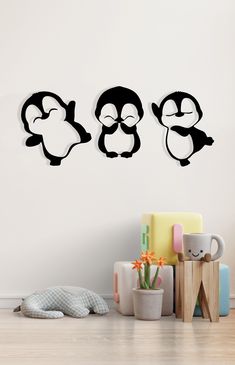 three penguins with their eyes closed sitting on the floor in front of a white wall