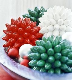 there are many different types of ornaments in the bowl on the table and one is red, white and green