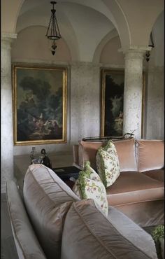 a living room with couches and paintings on the wall