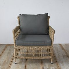 a wicker chair sitting on top of a wooden floor next to a white wall