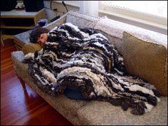 a man laying on top of a couch covered in fur