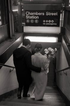 a man and woman walking up an escalator with flowers in their hand, black and white photograph