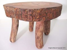 a small wooden stool made out of tree stumps on a white table with no one around it