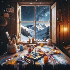 an artist's desk in front of a window with paint and brushes on it