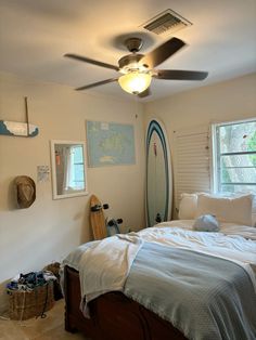 a bedroom with a surfboard on the wall and a ceiling fan in the corner