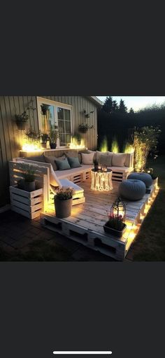 an outdoor seating area is lit up with lights and potted plants on the deck