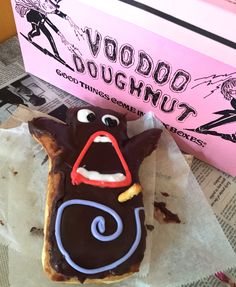 there is a chocolate doughnut with googly eyes on it next to a pink box