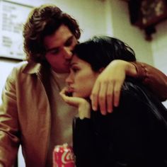 a man and woman kissing each other in front of a coke bottle on the counter