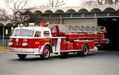 a red and white fire truck parked in front of a building with an open door