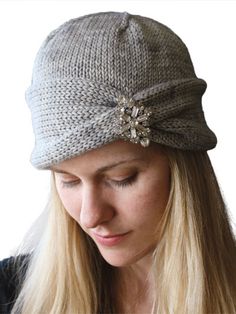 a woman wearing a gray knitted hat with a flower on the front and side