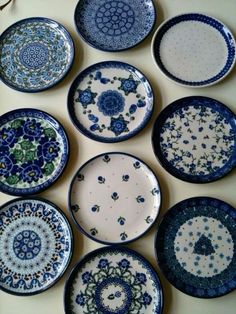 nine plates with blue and green designs are arranged in a circle on a white surface