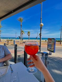 a man sitting at a table with a wine glass in front of him on the beach