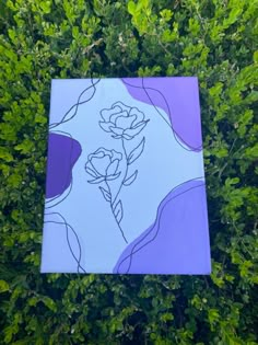 a purple and white painting sitting on top of a lush green field