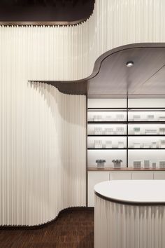 an empty counter in a store with white curtains on the wall and shelves behind it