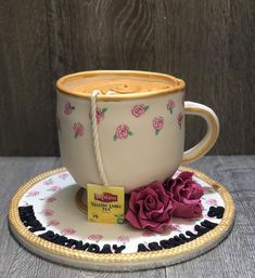 a cake shaped like a coffee cup and saucer with pink roses on the rim