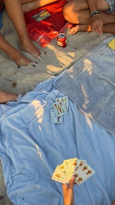 people sitting on the beach playing cards and drinking beer