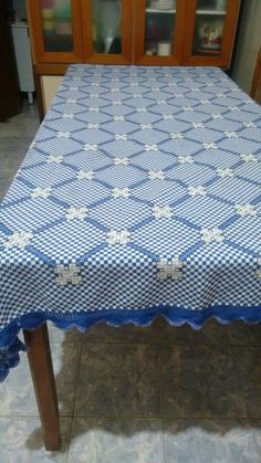 a blue and white table cloth on top of a wooden table with chairs in the background