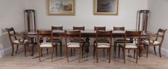 a dining room table with six chairs and two pictures on the wall above it in an empty room