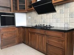 an empty kitchen with wooden cabinets and black counter tops in the middle of the room