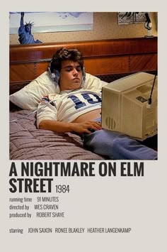 a man laying in bed with headphones on and looking at an electronic device that reads a nightmare on elm