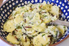 a blue and white bowl filled with potatoes covered in cheese, herbs and seasoning