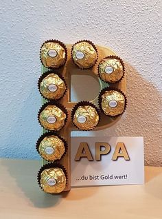 the letter p is made out of chocolates and wrapped in gold wrappers with a sign that says apa