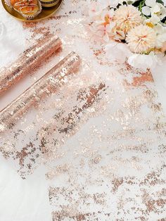 the table is covered with rose gold sequins and pink flowers, along with candles