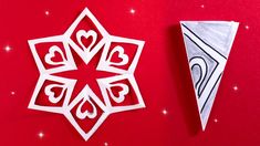 an origami snowflake next to a paper christmas decoration on a red background