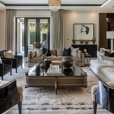 a living room filled with furniture and a chandelier hanging from the ceiling over a glass top coffee table