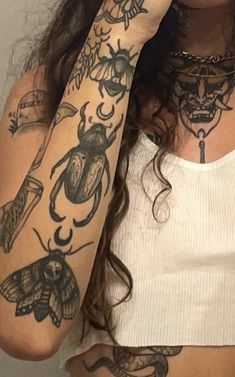 a woman with many tattoos on her arm and shoulder, covering her eyes while she holds her hand up to her face