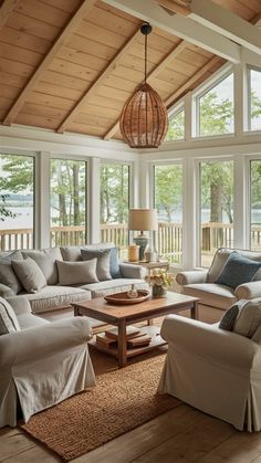 a living room filled with lots of furniture under a wooden beamed ceiling and windows