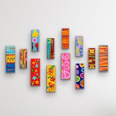 a group of colorful pieces of art hanging on a white wall next to each other