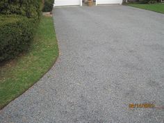 a driveway with gravel and grass in front of a house