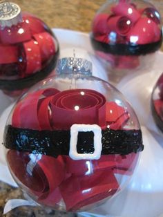 red glass ornaments with santa's belt on them are sitting on a table top