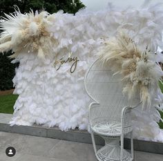 a white chair sitting in front of a large feathered wall with the word enjoy written on it