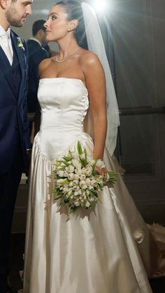 a bride and groom are standing together in front of the light shining through the window