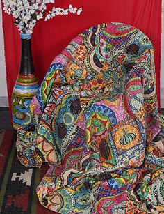 a vase with some flowers on top of it next to a cloth covered tablecloth