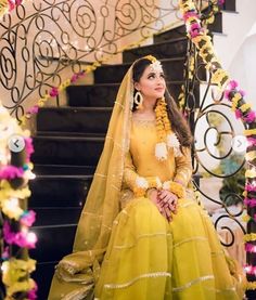 a woman in a yellow dress sitting on stairs with flowers around her neck and head