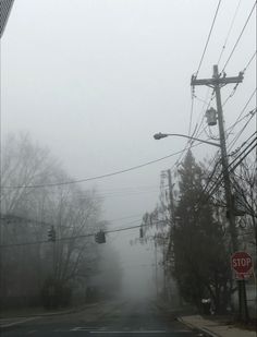 a foggy street with traffic lights and power lines