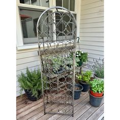 a metal plant stand sitting on top of a wooden deck next to potted plants