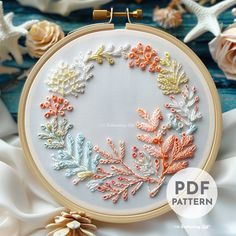 an embroidery pattern with flowers and leaves in the hoop on top of white satin fabric